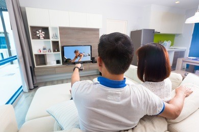 happy family watches television while sitting on the sofa.