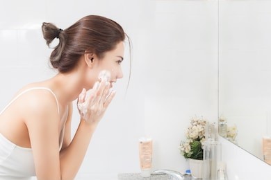 woman happy cleanses the skin with foam in bathroom.