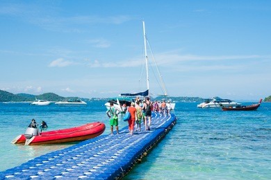 tourists return from the banana beach of coral (ko he) island and go to the motor boat. rawai, phuket, thailand
