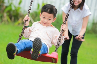 happy family having fun on a swing ride at a garden.