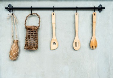 the wooden kitchenware hang on the black hanger with the background of gray cement wall, retro decoration concept.