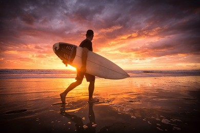 surfer running on the beach at sunrise with reflections