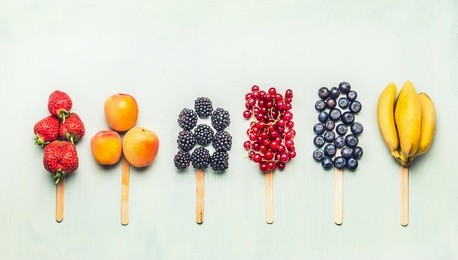fruits and berries assorted popsicles on light turquoise background, top view.healthy food and vegetarian eating concept
