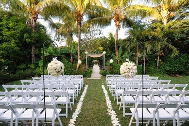 a flower bouquet with roses in front of rows of chairs at a wedding ceremony