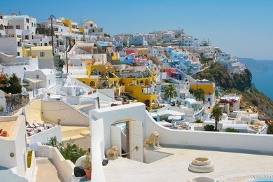 landscape of city fira with traditional houses on island of santorini, greece. arch with statue of lions is in front.