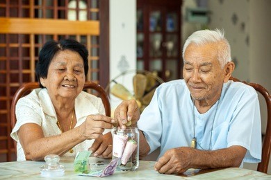 senior couple counting money with glass bank
