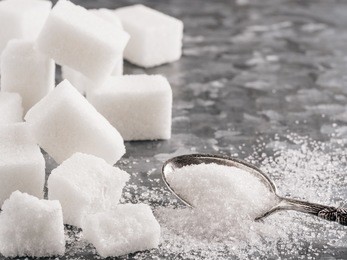sugar background. sugar cubes and granulated sugar in spoon. white sugar on gray galvanized iron background. copy space.