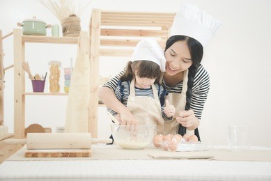 happy family in the kitchen. asian mother and her daughter preparing the dough to make a cake.