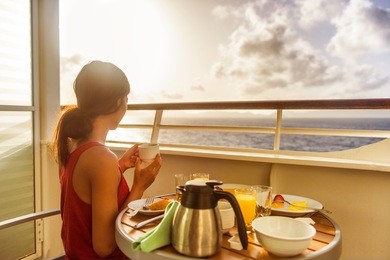 cruise ship luxury travel woman eating breakfast from room service on suite balcony enjoying morning view of caribbean ocean. summer sailing vacation lifestyle people drinking coffee.