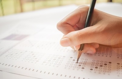 hand student testing in exercise and taking fill in exam carbon paper computer sheet with pencil at school test room, education concept