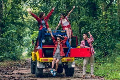 happy asian young travellers with 4wd drive car off road in forest, young couple looking for directions on the map and another two are enjoying on 4wd drive car.