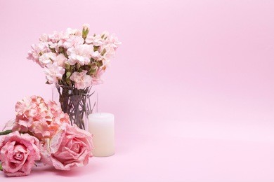 pink carnations in glass vases, pink roses, beige hydrangea and scented candle on pink background. sweet and romantic interior.