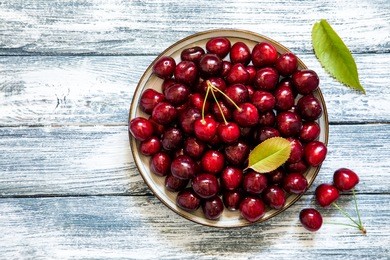 fresh cherry on plate on wooden blue background. fresh ripe cherries. sweet cherries.