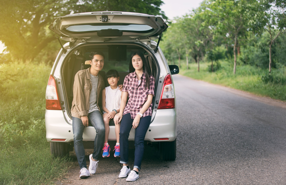 happy little girl  with asian family sitting in the car for enjoying road trip and summer vacation