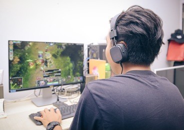 back view of young gamer playing video games at home
