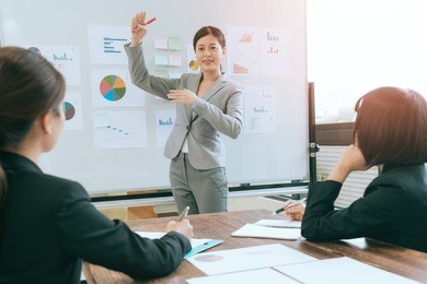pretty attractive business people meeting in office with whiteboard and company leader talking future planning for employee.