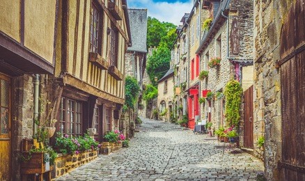 beautiful view of scenic narrow alley with historic traditional houses and cobbled street in an old town in europe with blue sky and clouds in summer with retro vintage instagram grunge filter effect