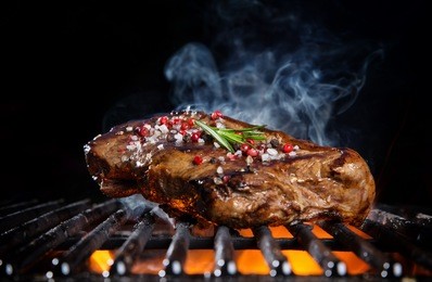 beef steak on the grill grate, flames on background. barbecue and grill, delicious food.
