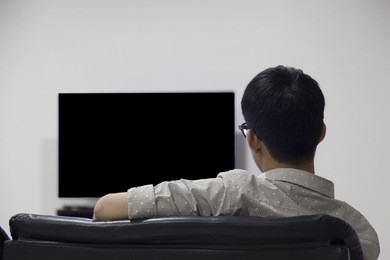 glasses black head asian men watching blank tv sitting on sofa couch