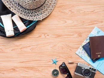 travel in summer concept flat lay or top view photo with camera, passport, sunglasses, hat, map are prop on wooden background.
