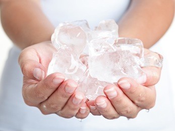ice cold hands. woman hands holding ice cubes - closeup.