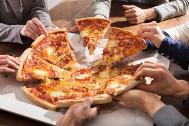 close-up of businesspeople taking slice of pizza from the box