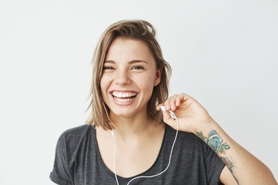 nice young girl in headphones laughing looking at camera over white background.