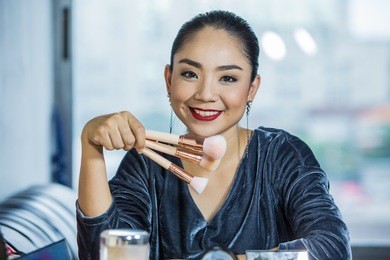 brunette woman applying make up  closeup portrait of woman with makeup brush near face