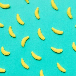 sweets in the shape of bananas on a blue background. minimal flat lay. party food
