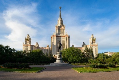 beautiful perspective of main building of moscow state university or msu and monument of greatest russian scientist lomonosov with flowers, green trees, blue cloudy sky. education in moscow, russia