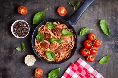 spaghetti with meatballs, tomato sauce and ingredients. italian american dish. meatballs pasta in a pan. top view. traditional italian cuisine. dark rustic wooden table. making dinner with pasta