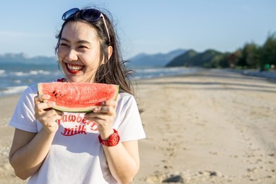 woman eating watermelon  feeling happy on the beach. copy space