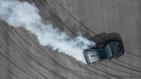 top view aerial photo from flying drone of a professional driver drifting car on asphalt track.