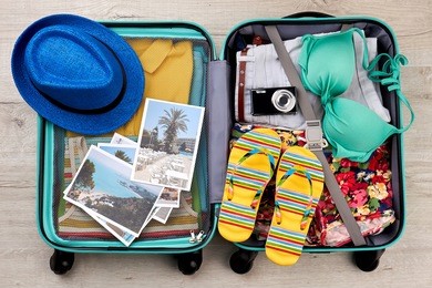 suitcase full of beach accessories. opened bag with summer stuff, top view.