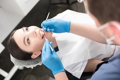 odontologist examining teeth of happy woman