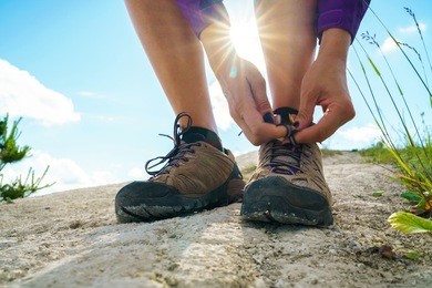 hiking shoes - woman tying shoe laces. closeup of female tourist getting ready for hiking