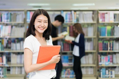 group of asian students studying together in library at university. university students.
