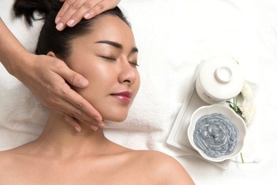 close up of beautiful young asian woman lying with closed eyes and preparation face or head massage in spa or wellness, beauty healthy lifestyle and relaxation concept