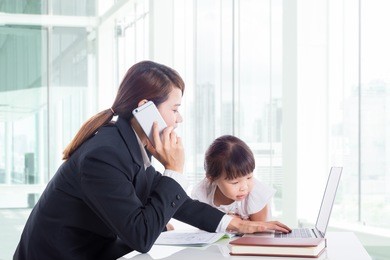 asian mother who is a businesswoman working in the office while the daughter wants her mother to read the book , women working outside the home concept.