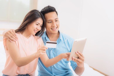 happy asian couple using tablet and credit card for online shopping