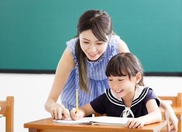 young teacher helping child with writing lesson
