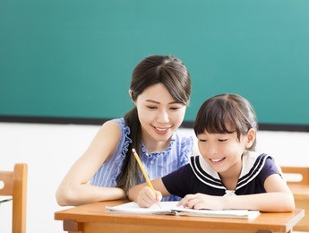 young teacher helping child with writing lesson
