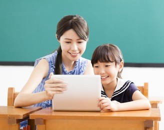 young teacher helping child with computer lesson