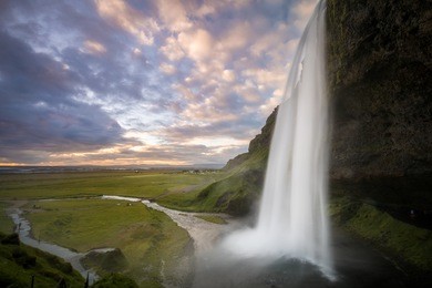 seljalandsfoss is a waterfall located in the south region in iceland right by route 1. dramatic and gorgeous scene. popular tourist attraction.