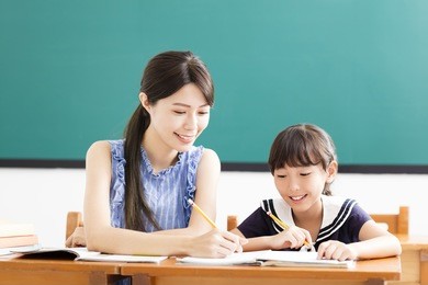 young teacher helping child with writing lesson