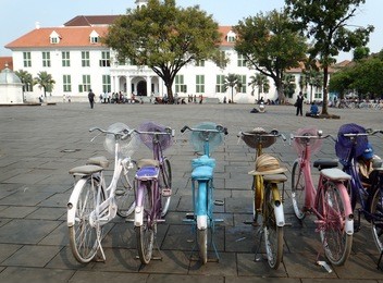 a row of colorful bikes in front of the museum fatahilah (jakarta, indonesia) ready for tourists