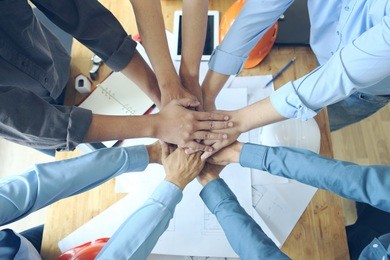 work group of gngineer  people joining hands.(tool ,paper and safety helmet)