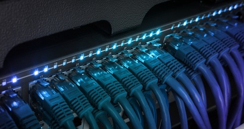 network server panel, switch and patch cord cable in data center glowing in the dark. blue led