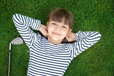 cute girl with driver lying on golf course