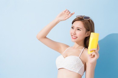 woman take sunscreen on the blue background